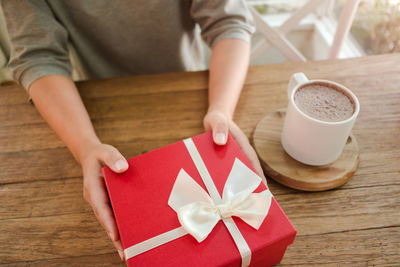 Midsection of woman holding coffee cup on table