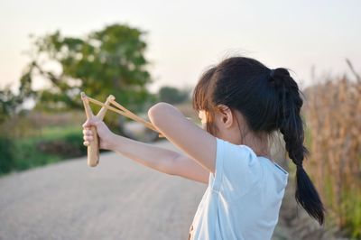 Rear view of girl playing with toy against sky