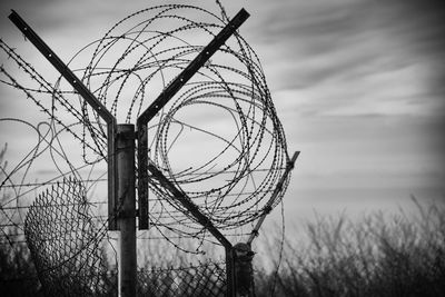 Low angle view of barbed wire fence against sky