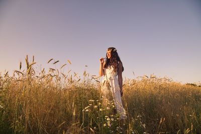 Young woman standing on field against clear sky