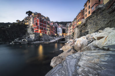 Buildings by river against sky