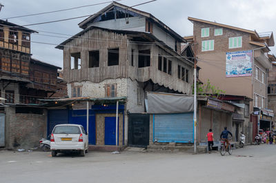 Cars on street by buildings in city against sky