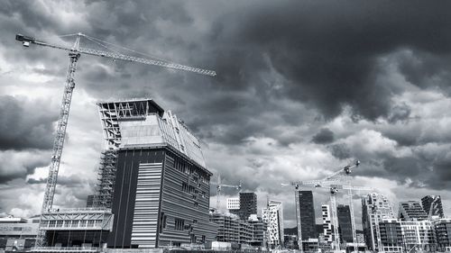 Low angle view of crane at construction site against sky