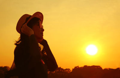Silhouette of a woman in hat looking up at the sunrise sky