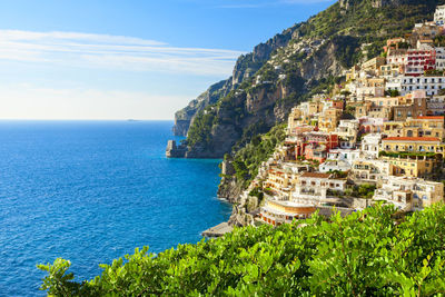 Residential district on mountain by sea against sky