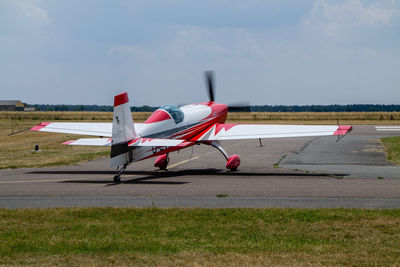 Airplane flying over airport runway against sky