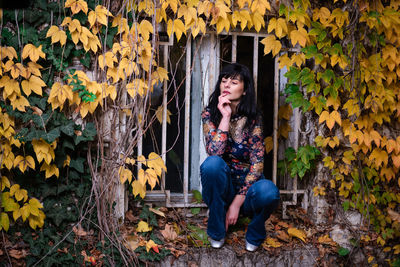 Full length of woman sitting on plant during autumn