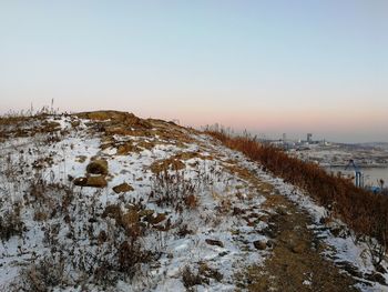 Scenic view of snowy field against clear sky during sunset