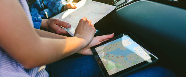 Young couple reading map on digital tablet in car