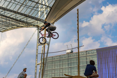 Low angle view of people on bridge against sky