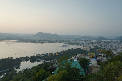 High angle view of townscape by sea against sky during sunset