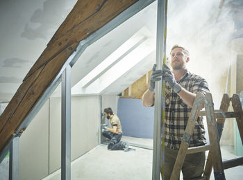 Construction worker measuring metal for drywall at site