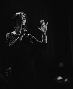 Full length of woman standing against black background