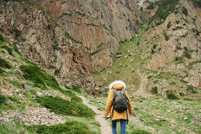 Rear view of woman walking on rocks against mountain