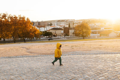 Cute kid walking on street in down