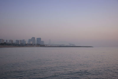 Scenic view of sea by buildings against clear sky