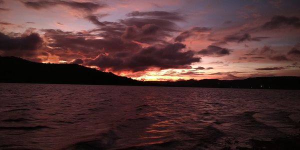 Scenic view of sea against dramatic sky during sunset