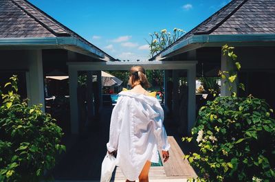 Woman standing by building against plants