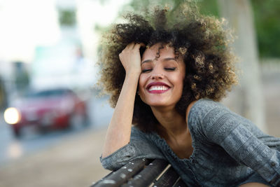 Smiling young woman with curly hair in city