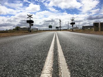 Close-up of road against cloudy sky in city