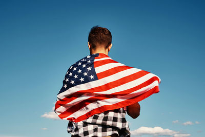 American flag outdoors. man holds usa national flag against blue cloudy sky. independence day