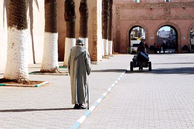 Rear view of people walking on street in city