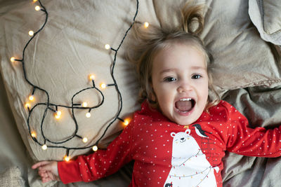 Portrait of cute baby girl lying down on bed at home