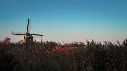 Windmill on field against clear sky