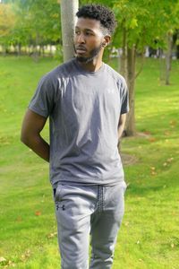 Young man standing on grassy field at park