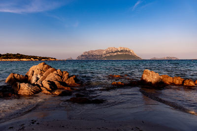 Rock formations on shore against blue sky