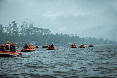 People rafting on river against sky