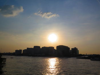 City by sea against sky during sunset