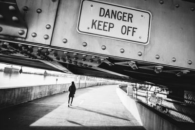 Close-up of warning sign on metal over footpath