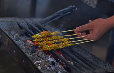 Midsection of person preparing food on barbecue grill