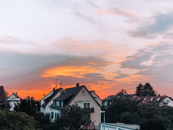 Houses and trees against sky during sunset