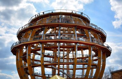 Low angle view of ferris wheel against cloudy sky
