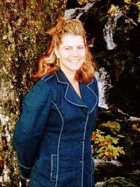 Portrait of smiling young woman standing against plants