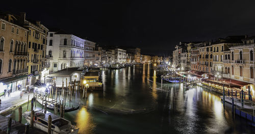 Canal amidst illuminated buildings in city at night