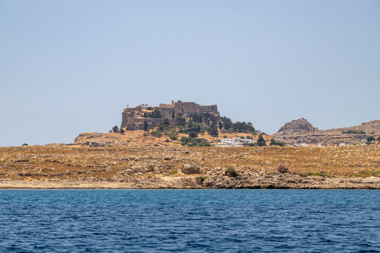 CASTLE BY SEA AGAINST CLEAR BLUE SKY