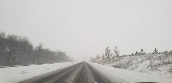 Road amidst trees against sky during winter