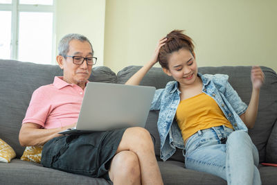 Young man using mobile phone while sitting on sofa