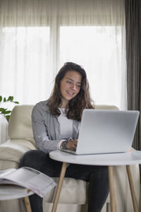 Young woman using phone while sitting on table