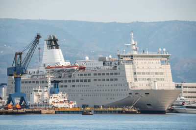 Luxurious large cruise ship moored at messina harbor with mountain in background