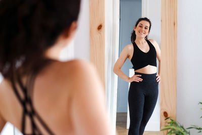 Young woman looking away while standing at home