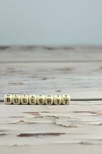 Close-up of text on table at beach against sky