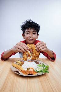 Portrait of young woman eating food on table