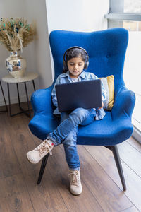 Girl using laptop sitting on chair at home