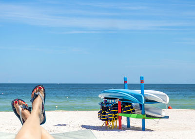 Rear view of woman relaxing on beach against sky