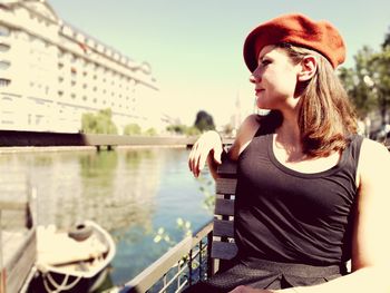 Close-up of young woman sitting on riverbank against clear sky