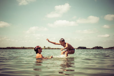 Carefree mother and son having fun in the water during summer day. copy space.